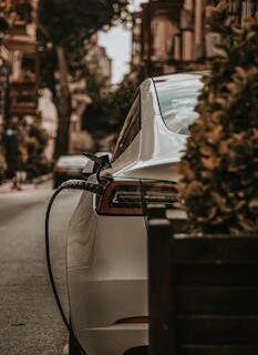 White electric car charging on an urban city street, emphasizing eco-friendly transportation.